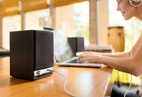 Audioengine A2-HD on a wooden dorm desk for listening.