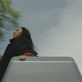 Bang & Olufsen Beolit 20 Grey Mist in-use with smartphone during outdoor gathering.