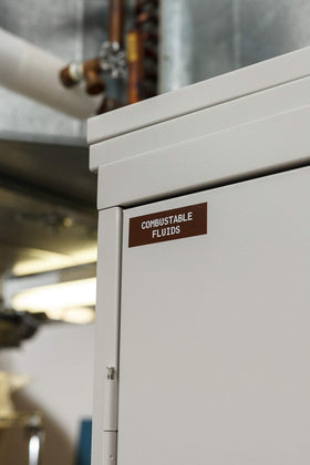 brady white-on-brown label applied to curved pipe, showing strong adhesion and legibility