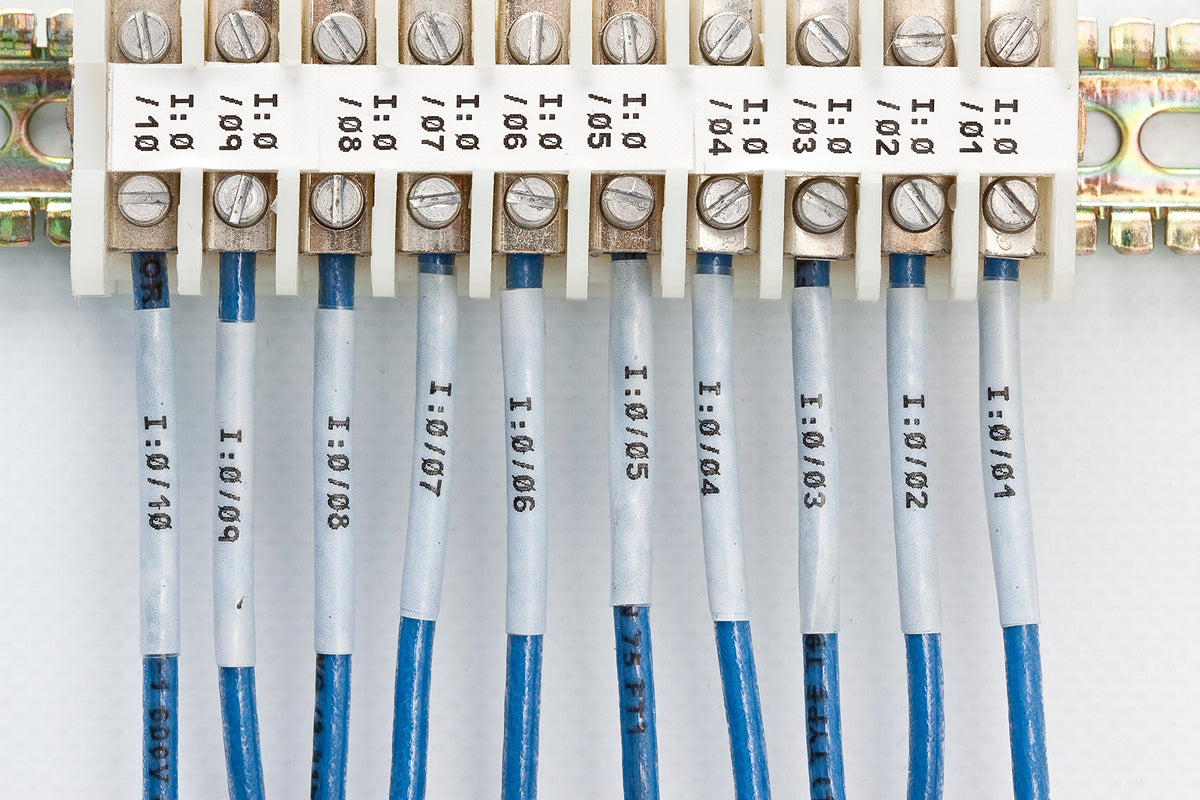 Brady tape roll beside ruler showing 0.375 inch width and length clarity