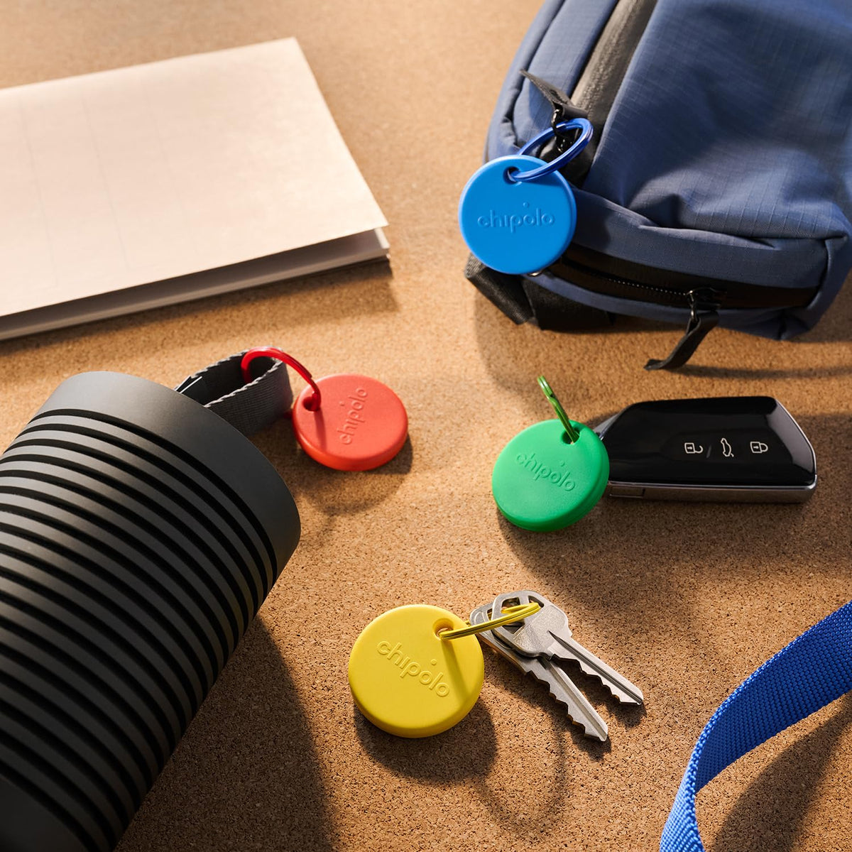 Chipolo POP yellow next to keys illustrating scale and portability