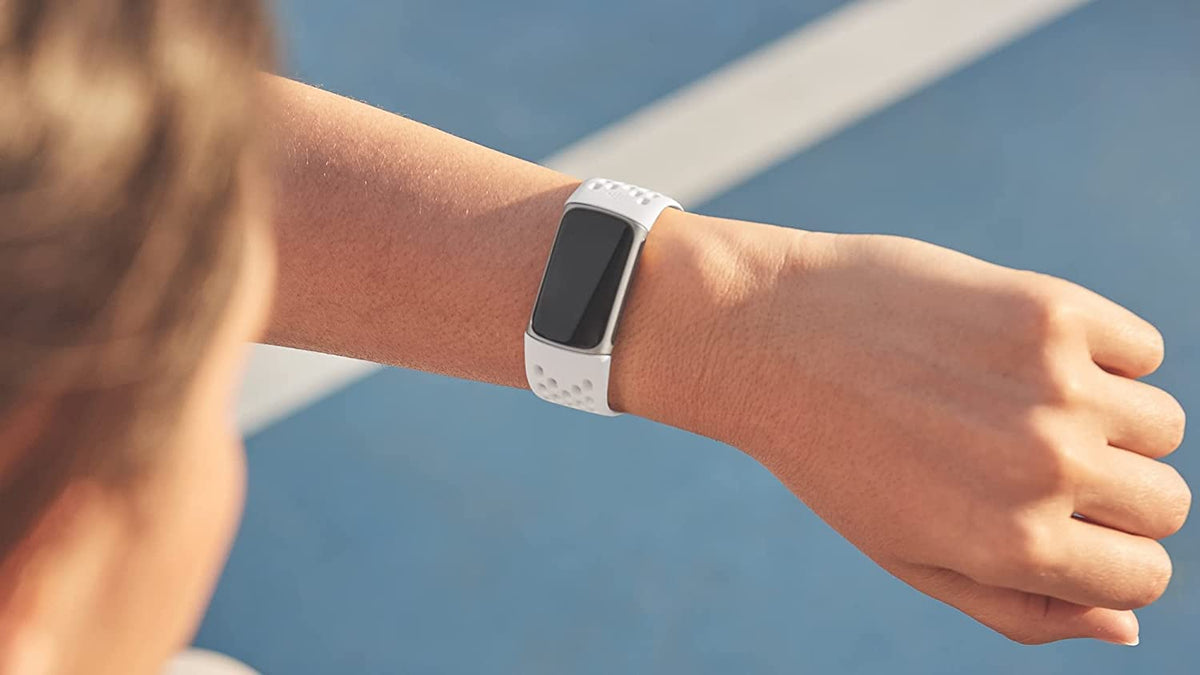 Fitbit frost white band next to Charge tracker shows sizing and compatibility