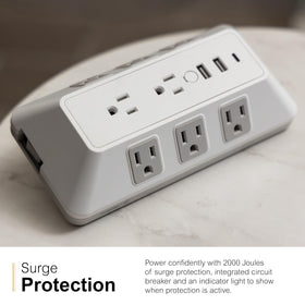 GE surge tap in use on desk charging phone laptop and lamp for convenience