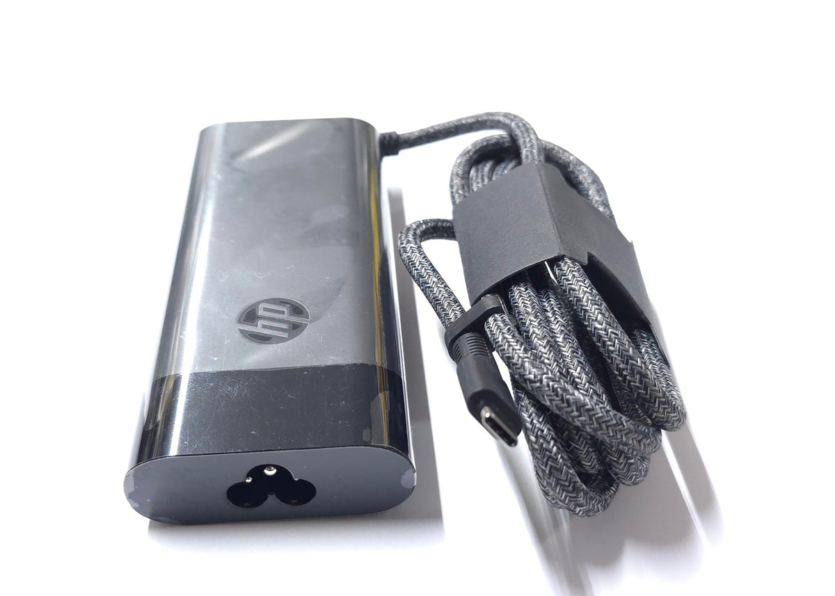 HP 100W USB-C Charger in use with a laptop setup powering the device.