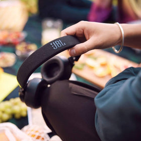 JBL LIVE670NC next to hand to show scale and lightweight handling benefit