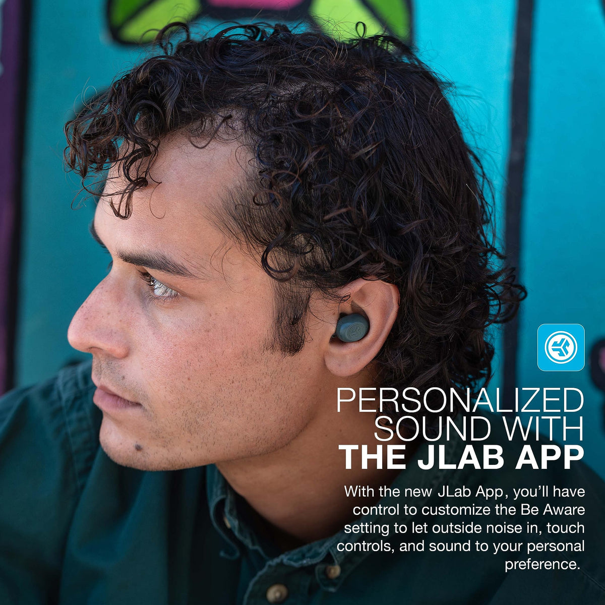JLab JBuds Mini charging case beside a phone showing scale and portability