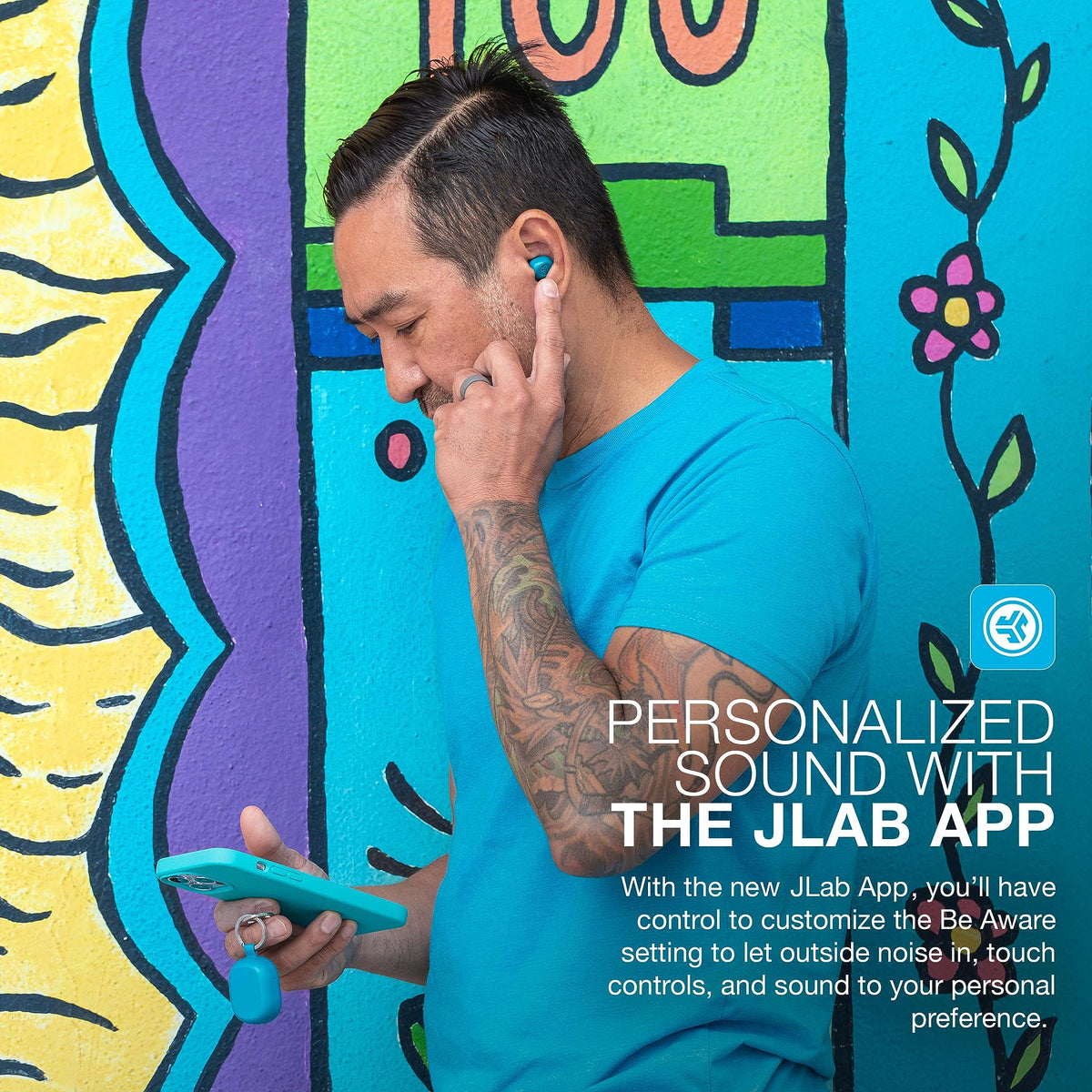JLab JBuds Mini beside a hand for scale illustrating small size and pocketability