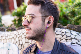 LUDOS Clamor purple case beside earbuds for protection during commute.