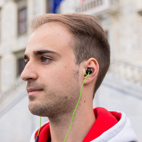 LUDOS Clamor earbuds plugged into a smartphone for commuting and hands-free listening