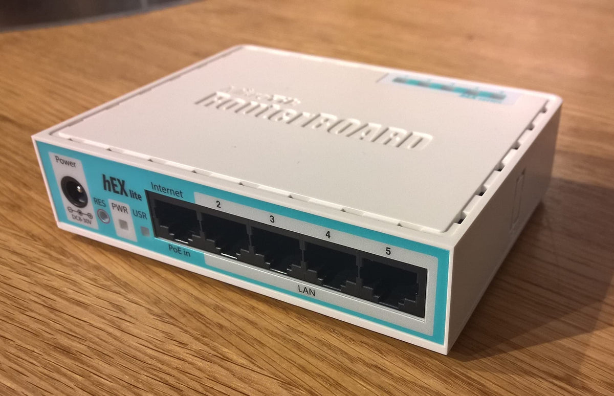 MikroTik RB750r2 on home office desk illustrating tidy wired network setup