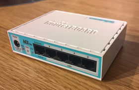 MikroTik RB750r2 on home office desk illustrating tidy wired network setup