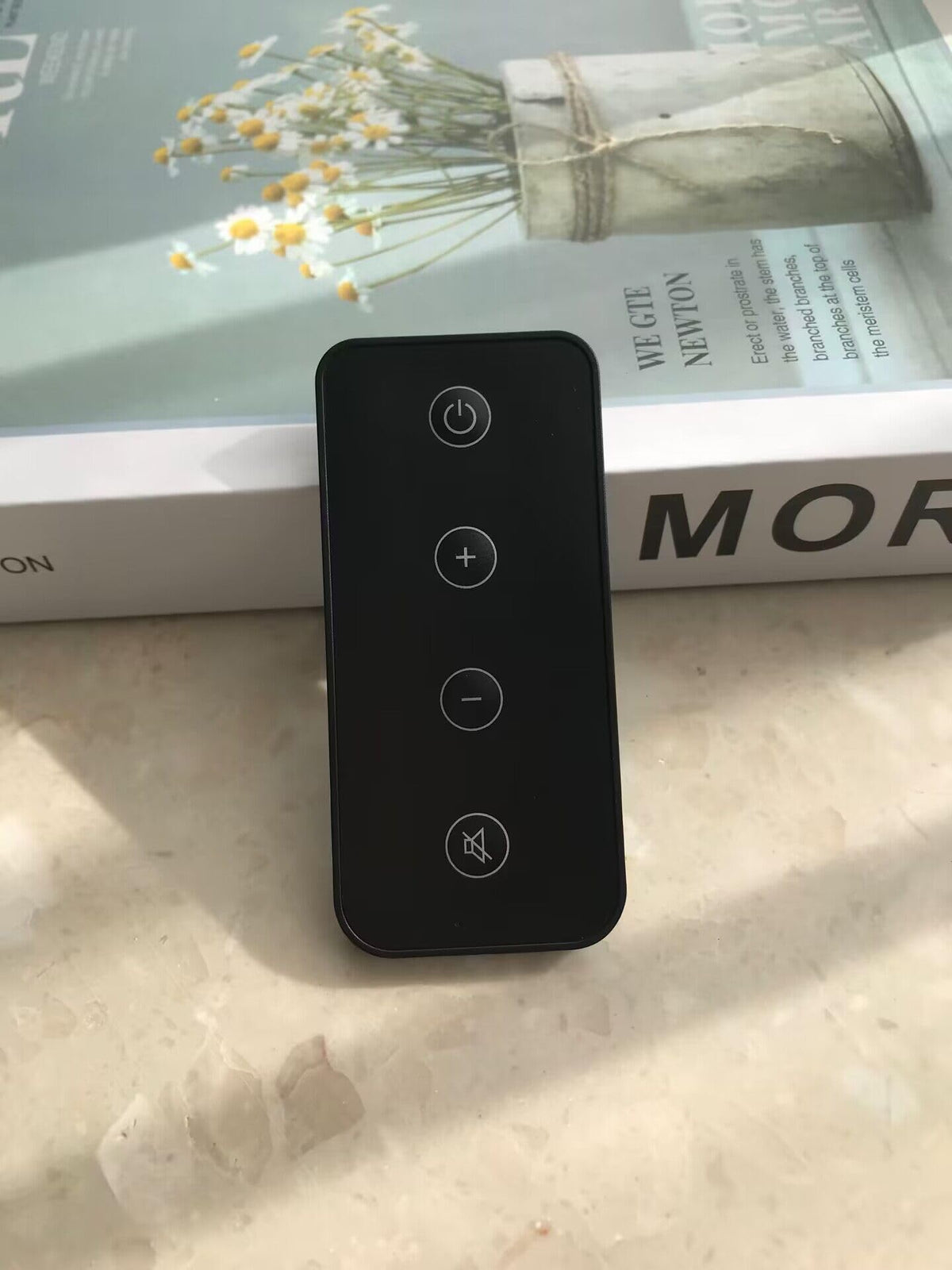 MONSIATUG remote held in hand to show compact size and ergonomic benefit