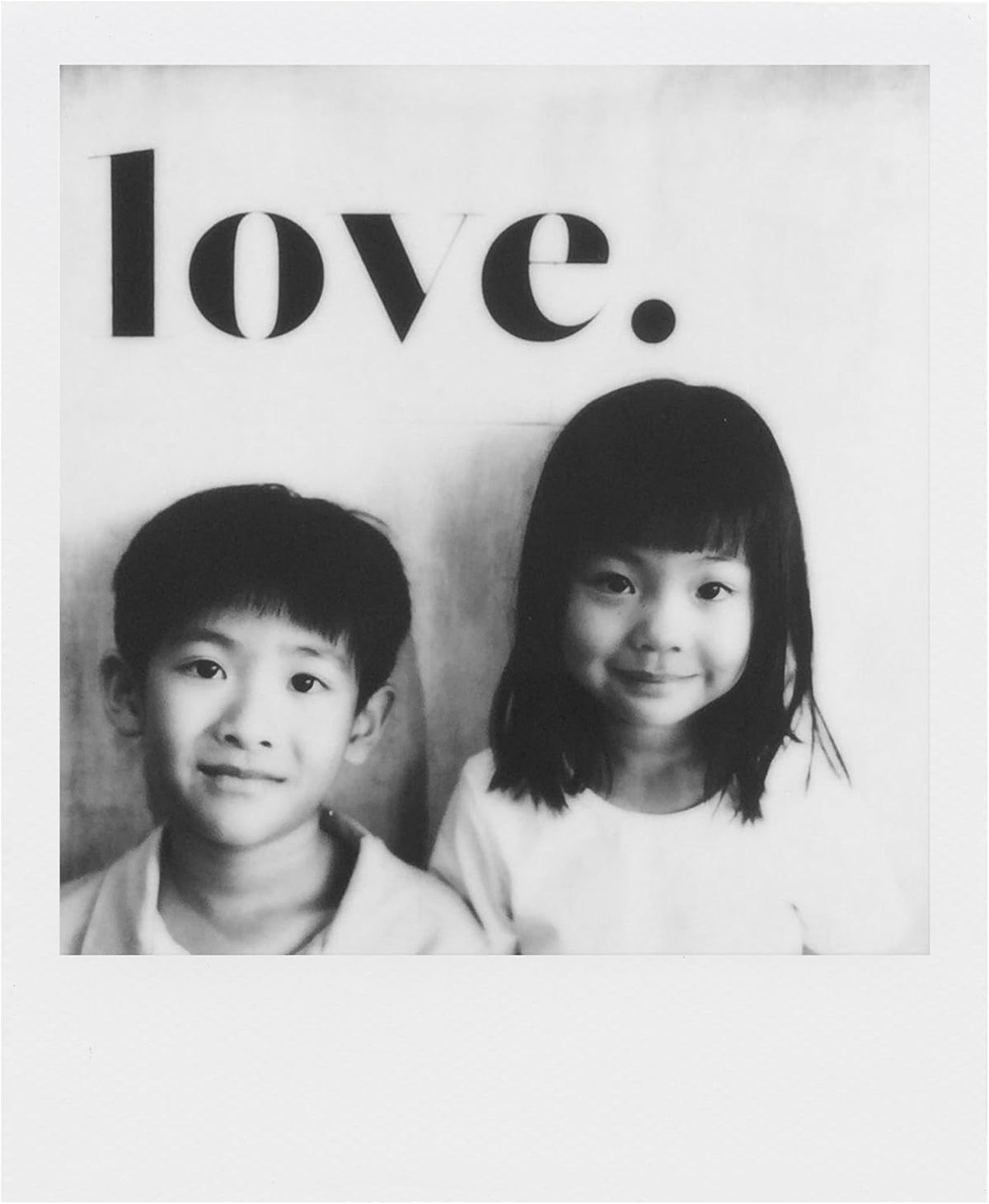 The Imaging World polaroid black & white film beside a camera on table for instant photo moments