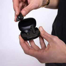 Skullcandy Smokin’ Buds charging case next to phone for size and scale