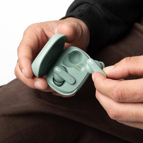 Skullcandy Smokin’ Buds next to coin for scale, shows compact charging case portability