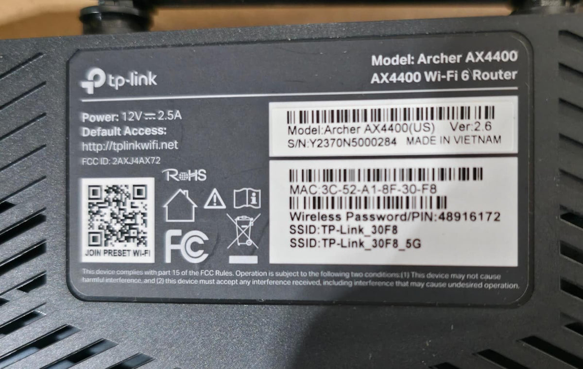TP‑Link Archer AX4400 next to a book showing compact router size and placement flexibility