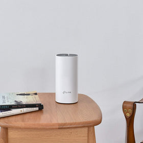 TP-Link Deco W2400 next to a smartphone and book showing compact size and space-saving benefit