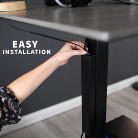 VIVO DESK-AC01-1MB standing-desk use shows safe cord routing during height adjustments.